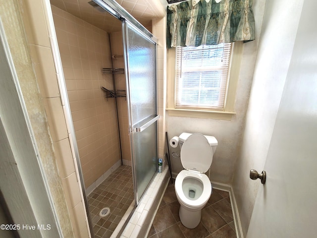 bathroom featuring tile patterned flooring, toilet, and a shower with shower door