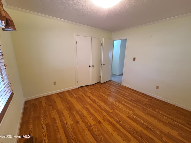 unfurnished bedroom featuring ornamental molding, light hardwood / wood-style floors, and a textured ceiling