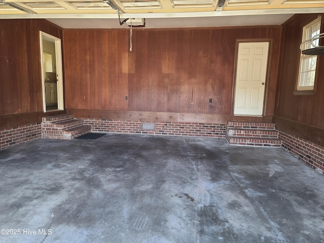 garage featuring a garage door opener and wooden walls