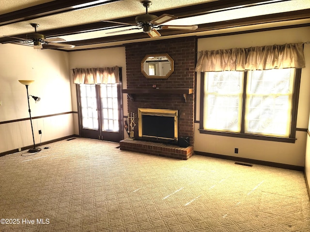 unfurnished living room with a brick fireplace, a textured ceiling, carpet floors, beamed ceiling, and ceiling fan