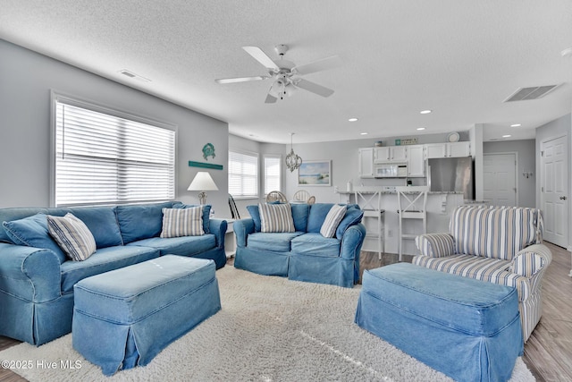 living room featuring a textured ceiling, ceiling fan, and light hardwood / wood-style flooring