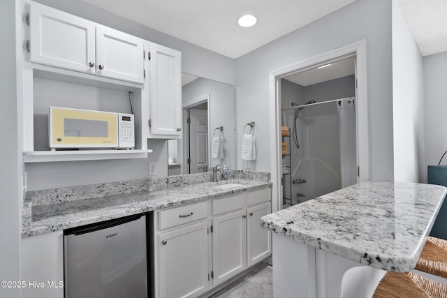 kitchen featuring a kitchen breakfast bar, white cabinetry, sink, and stainless steel refrigerator