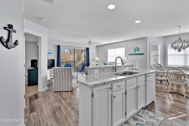 kitchen with pendant lighting, sink, white cabinets, a kitchen island with sink, and white dishwasher