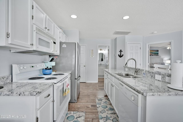 kitchen with sink, white cabinets, white appliances, light hardwood / wood-style floors, and a textured ceiling