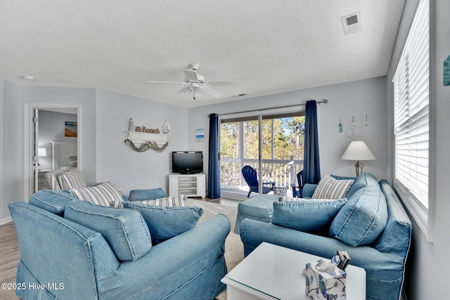 living room featuring hardwood / wood-style flooring, a textured ceiling, and ceiling fan