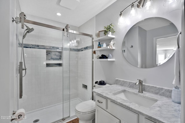 bathroom featuring vanity, toilet, a shower with door, and a textured ceiling