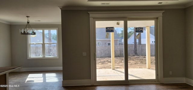 doorway featuring ornamental molding, wood-type flooring, and a notable chandelier