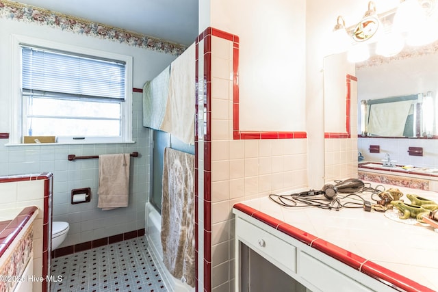 full bathroom featuring vanity, toilet, tile walls, and bath / shower combo with glass door