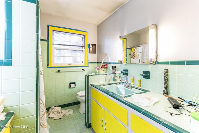 bathroom with tile patterned floors, vanity, toilet, and tile walls