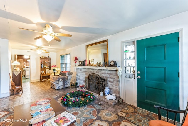living room featuring a stone fireplace and ceiling fan