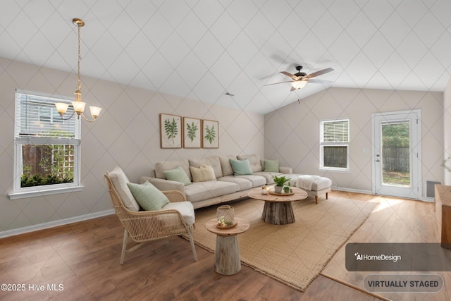 living area with baseboards, ceiling fan with notable chandelier, vaulted ceiling, and wood finished floors