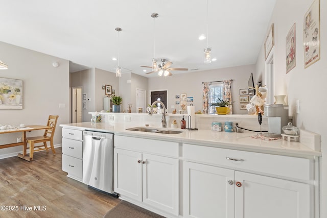 kitchen with pendant lighting, white cabinetry, dishwasher, sink, and light hardwood / wood-style flooring