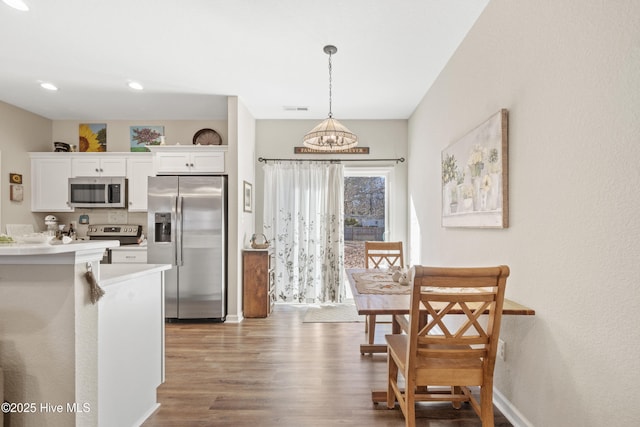 kitchen with white cabinetry, hanging light fixtures, light wood-type flooring, and appliances with stainless steel finishes