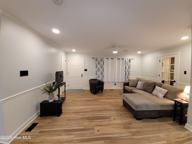 living room featuring ornamental molding, ceiling fan, and light wood-type flooring