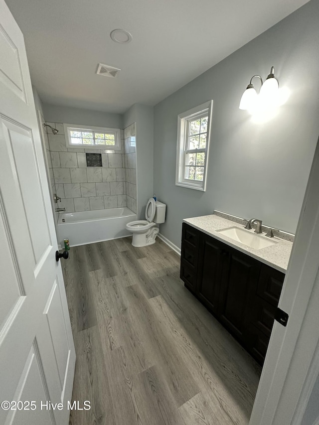 full bathroom featuring vanity, tiled shower / bath combo, plenty of natural light, and wood-type flooring