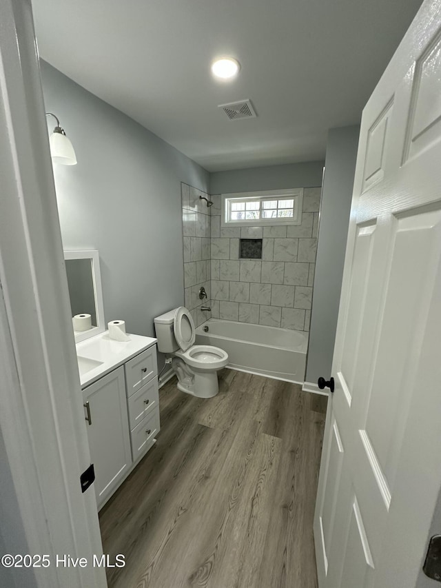 full bathroom featuring tiled shower / bath, vanity, toilet, and hardwood / wood-style floors