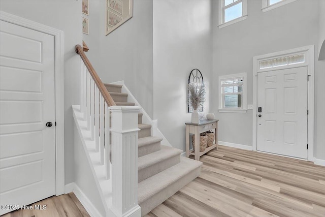 foyer with a healthy amount of sunlight, light hardwood / wood-style floors, and a towering ceiling