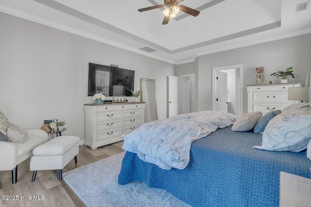 bedroom featuring crown molding, ceiling fan, a tray ceiling, and light hardwood / wood-style flooring