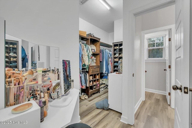 walk in closet with light hardwood / wood-style floors