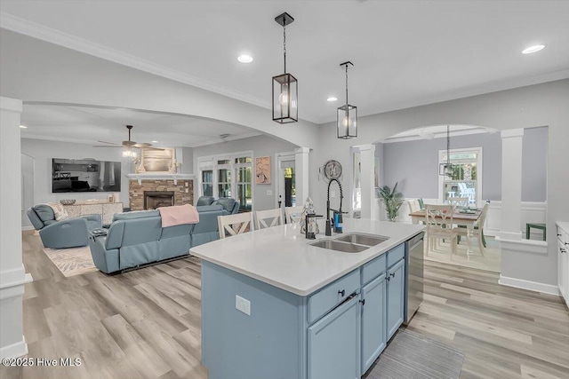 kitchen featuring decorative light fixtures, blue cabinets, dishwasher, sink, and a kitchen island with sink