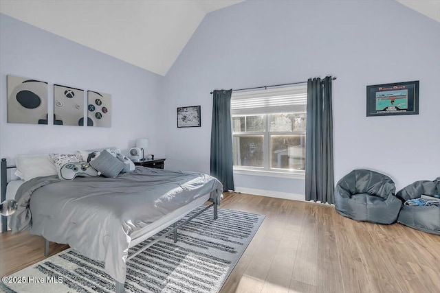 bedroom with hardwood / wood-style floors and high vaulted ceiling