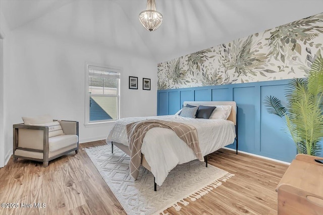 bedroom with a notable chandelier, light hardwood / wood-style flooring, and high vaulted ceiling