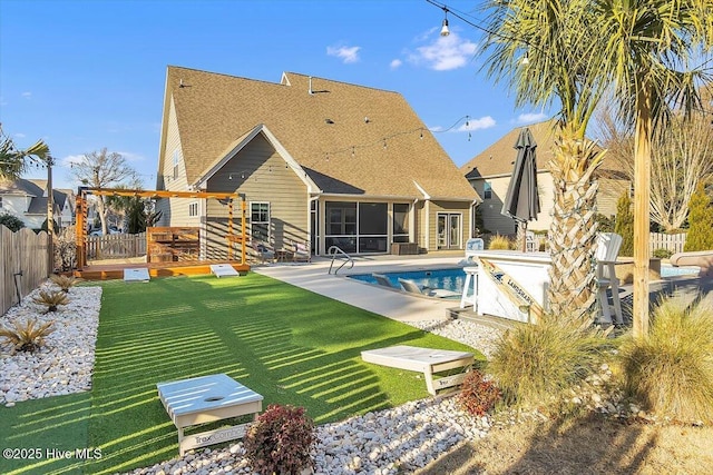 rear view of property featuring a fenced in pool, a sunroom, a lawn, and a patio area