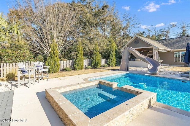 view of pool featuring a water slide, a patio area, and an in ground hot tub