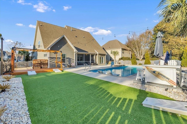 rear view of house with a fenced in pool, a yard, and a patio area