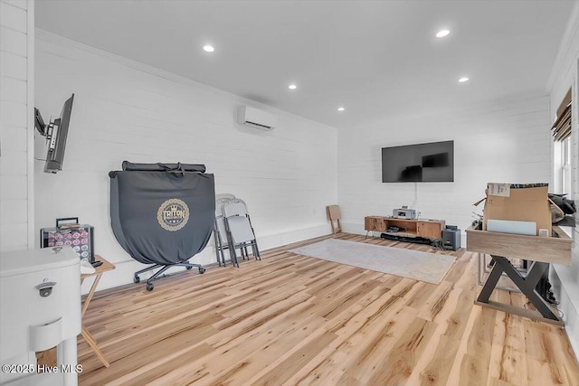 exercise room featuring crown molding, a wall mounted AC, and light hardwood / wood-style floors