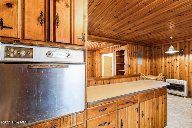 kitchen featuring heating unit, wood walls, hanging light fixtures, stainless steel oven, and wooden ceiling