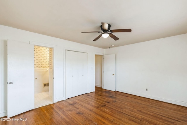 unfurnished bedroom featuring ceiling fan, wood-type flooring, connected bathroom, and a closet