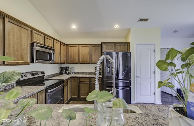 kitchen featuring stainless steel appliances, light stone countertops, and lofted ceiling