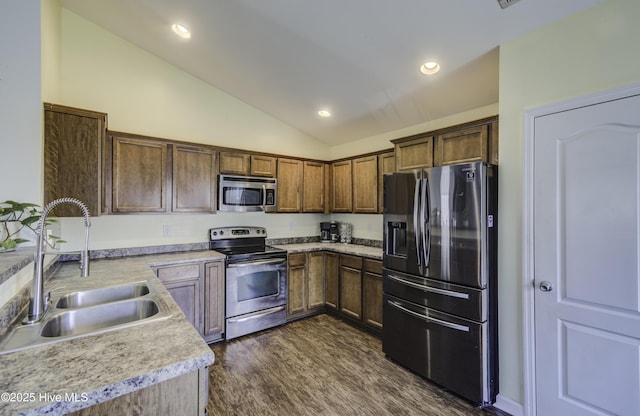 kitchen featuring dark wood finished floors, stainless steel appliances, lofted ceiling, light countertops, and a sink