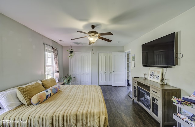 bedroom featuring multiple closets, ceiling fan, and dark hardwood / wood-style flooring