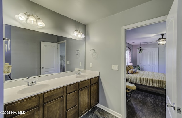 bathroom with double vanity, ensuite bath, baseboards, and a sink