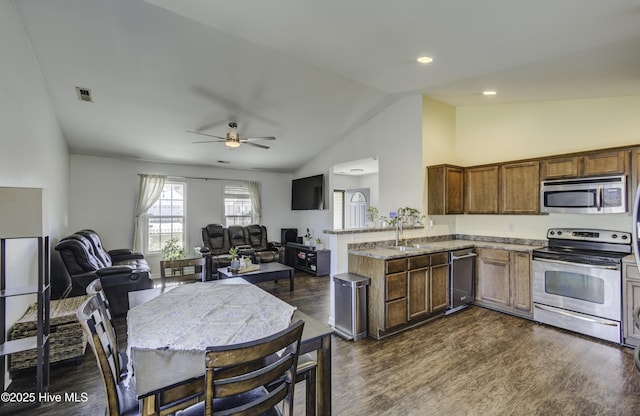 kitchen featuring open floor plan, a peninsula, appliances with stainless steel finishes, and dark wood finished floors