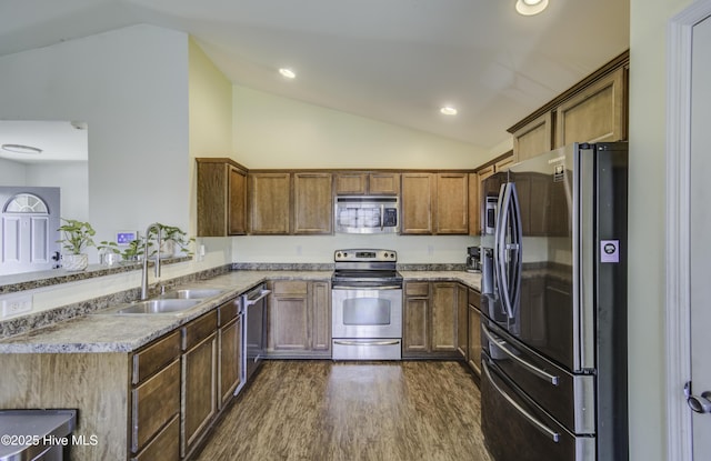 kitchen with appliances with stainless steel finishes, lofted ceiling, a sink, and a peninsula