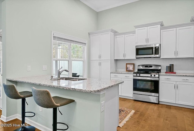 kitchen with stainless steel appliances, sink, white cabinets, and a kitchen breakfast bar