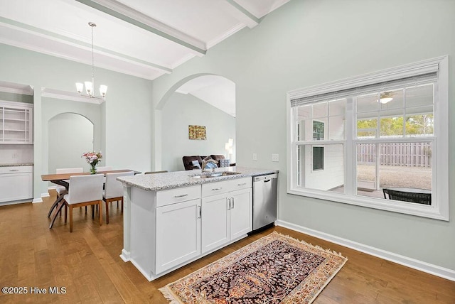 kitchen featuring light stone counters, white cabinets, decorative light fixtures, stainless steel dishwasher, and light wood-type flooring