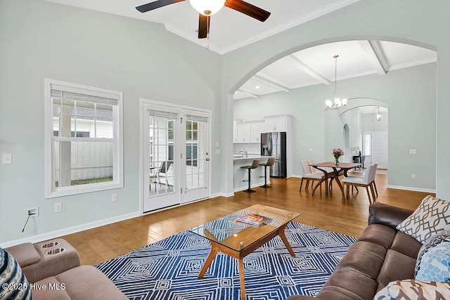 living room featuring beamed ceiling, wood-type flooring, ornamental molding, and ceiling fan with notable chandelier