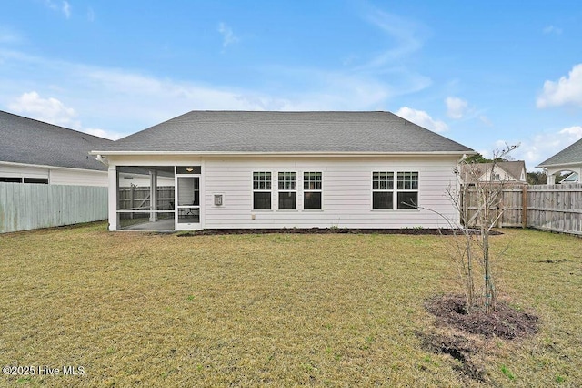 rear view of house featuring a yard and a sunroom