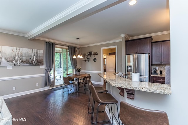 kitchen featuring stainless steel fridge, dark wood-type flooring, dark brown cabinets, light stone counters, and a kitchen bar