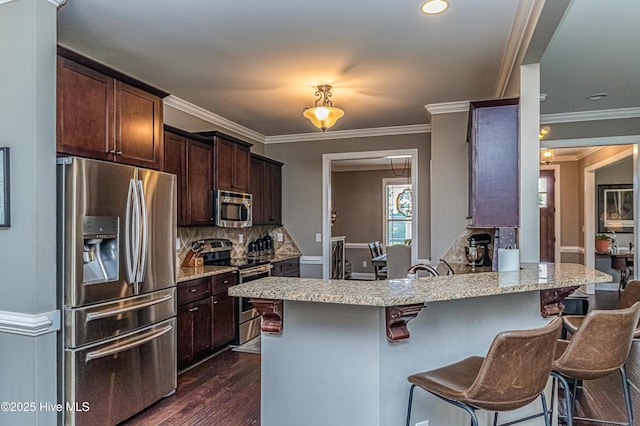 kitchen with dark brown cabinetry, dark wood-type flooring, stainless steel appliances, and a breakfast bar