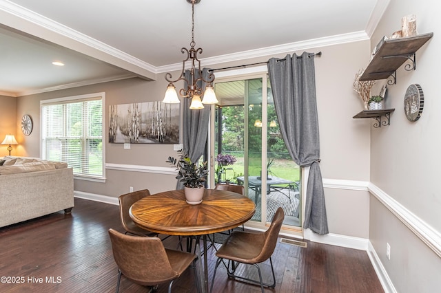 dining room with crown molding, dark hardwood / wood-style floors, and an inviting chandelier