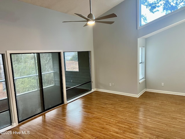 empty room featuring high vaulted ceiling, light hardwood / wood-style floors, and ceiling fan