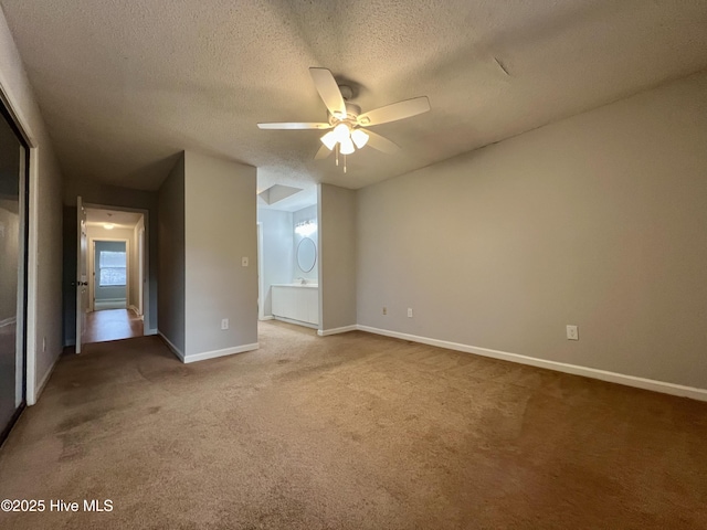 interior space featuring ceiling fan, carpet floors, connected bathroom, and a textured ceiling