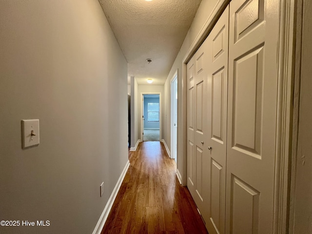 corridor with dark hardwood / wood-style flooring and a textured ceiling