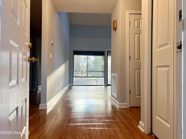 hall featuring wood-type flooring and a textured ceiling