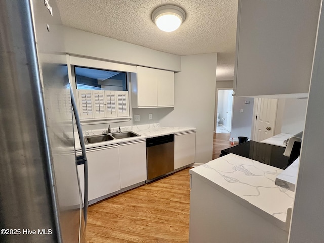 kitchen featuring dishwasher, sink, light wood-type flooring, white cabinets, and a textured ceiling